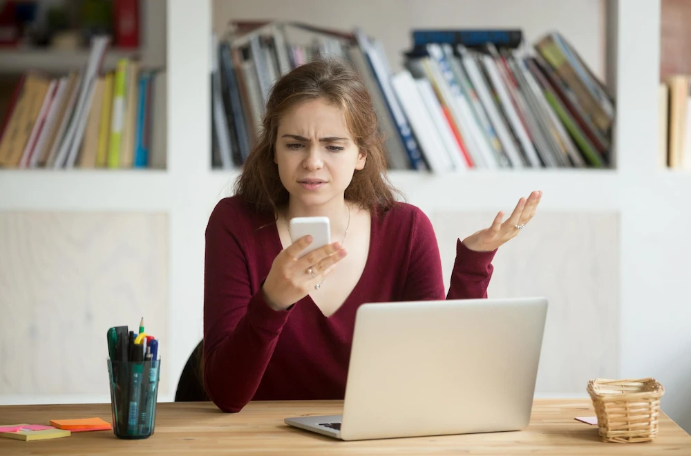 Une entrepreneure regarde un avis négatif sur son téléphone portable dans son commerce à Chartres