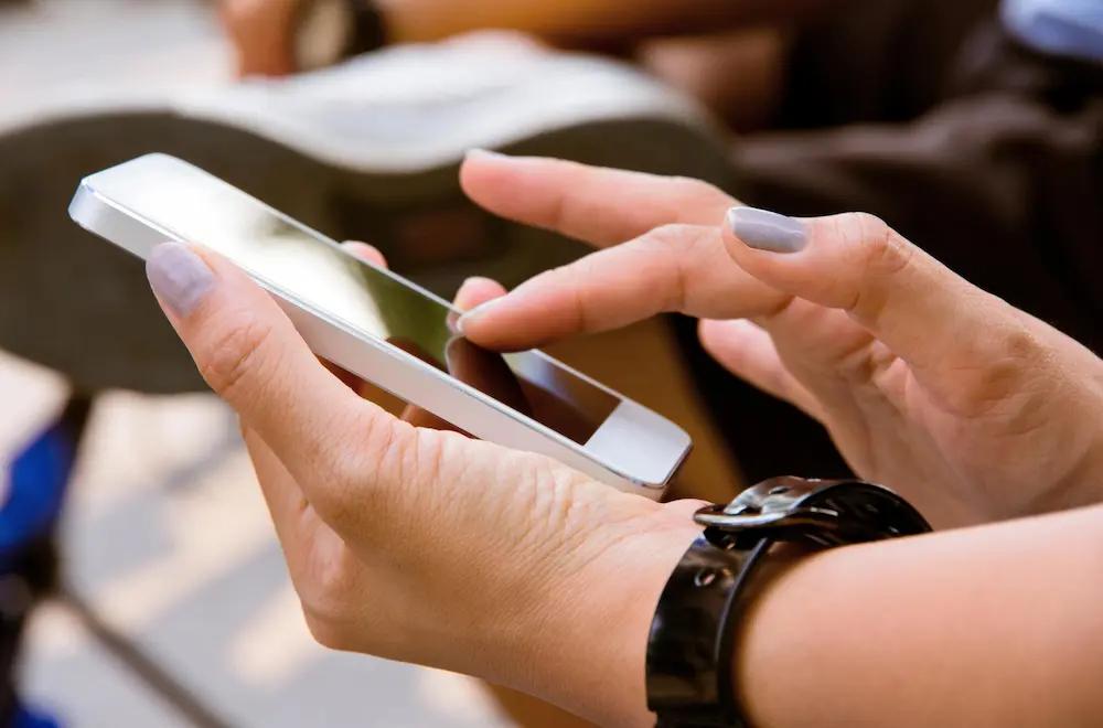 Une cliente à Chartres consultant les services d'un artisan local sur son téléphone portable en extérieur.