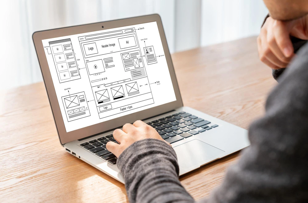 Un artisan indépendant assis à son bureau à Chartres, consultant son site internet professionnel sur-mesure sur son ordinateur portable